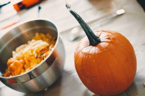 Pumpkin beside a bowl of seeds.