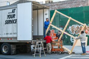 A team of movers loading a bed frame into a moving truck