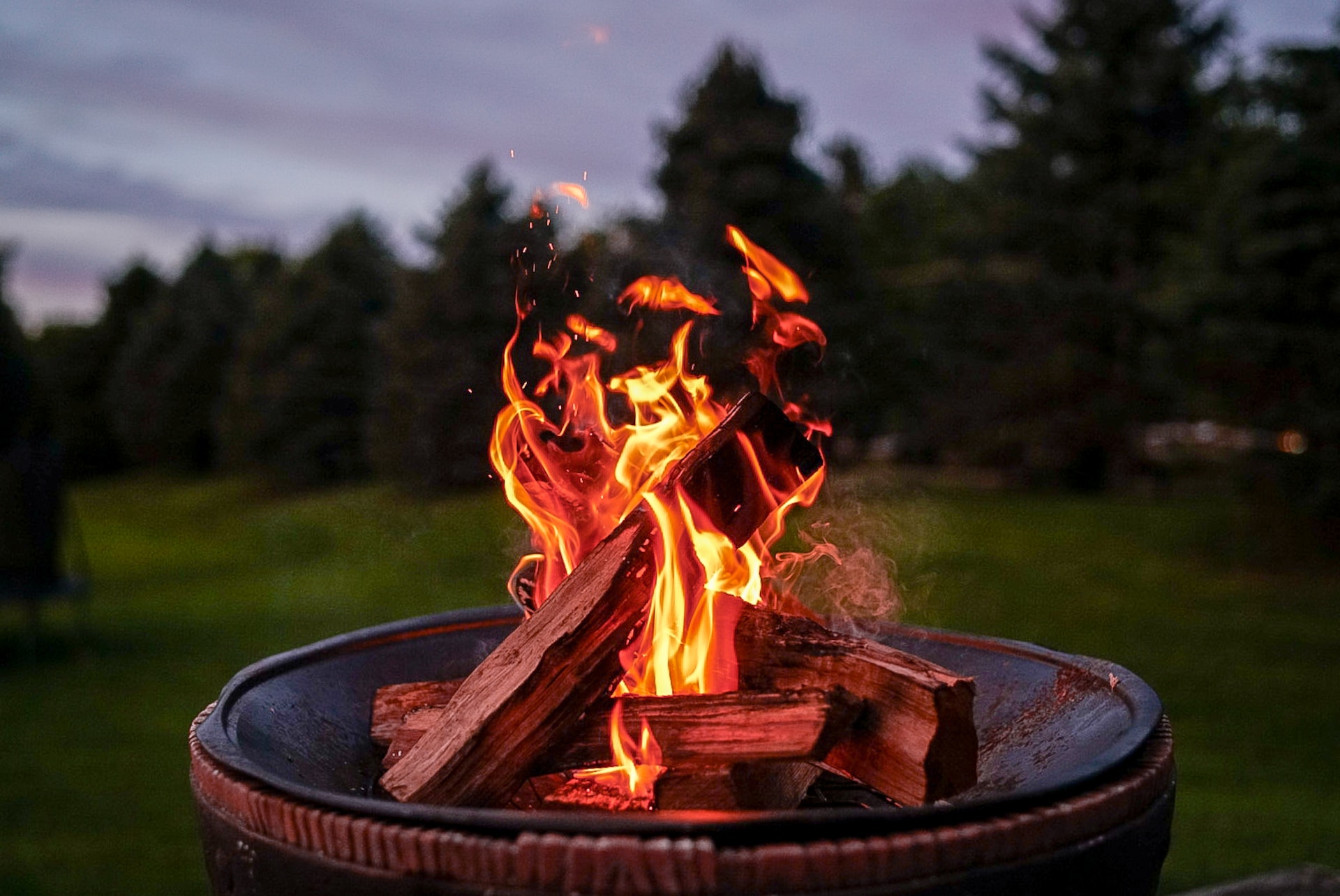 Flames rising from a fire pit outside at dusk.