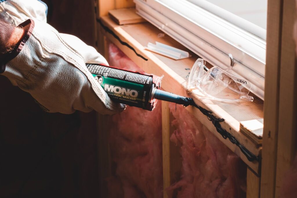 A construction professional applying sealant to a windowsill.