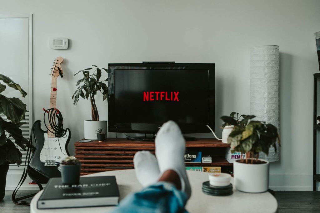 A person sitting in front of a TV whose screen shows the Netflix logo.