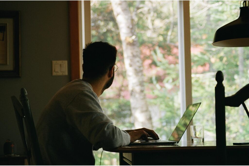 A remote worker in front of a computer looking outside.