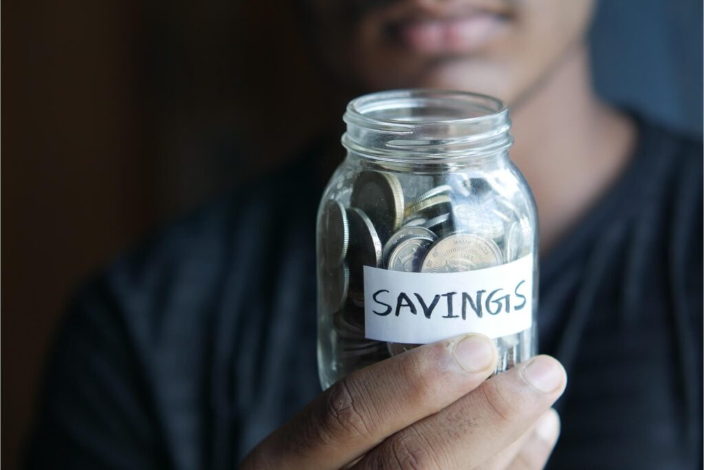 Man holding a jar of coins with a label saying savings.