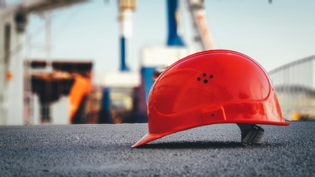 Red hard hat rests on the pavement at a construction site. 