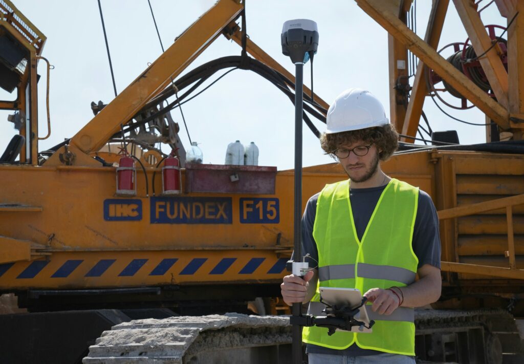 Construction worker uses technology for land surveying.