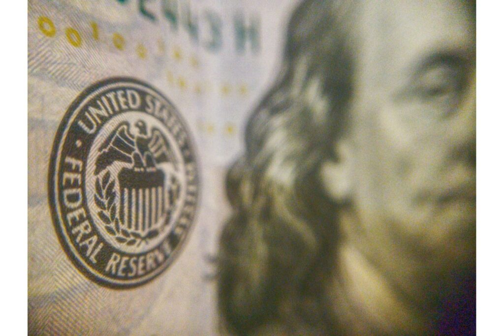 A close-up of a 100 US dollar bill that highlights the logo of the Federal Reserve