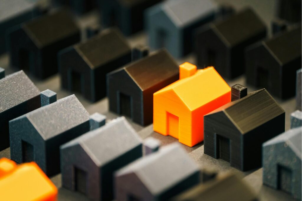 An orange miniature house surrounded by black miniature houses