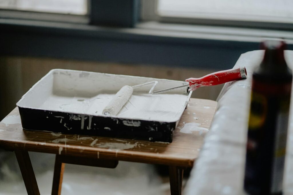pan of white paint with a paint roller sitting on a table