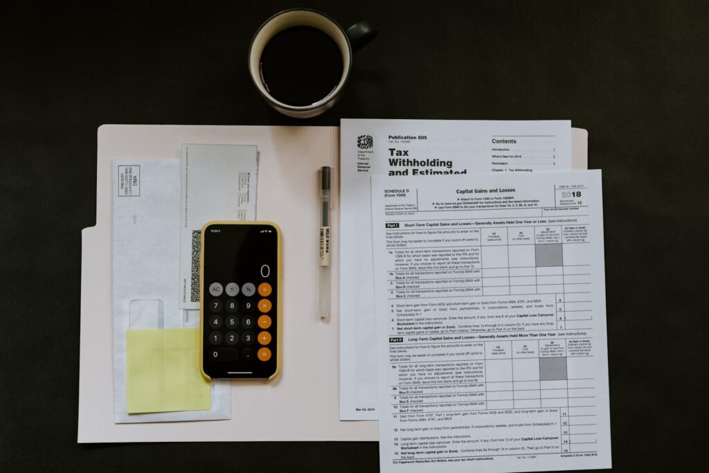 calculator with envelopes and tax papers on black background
