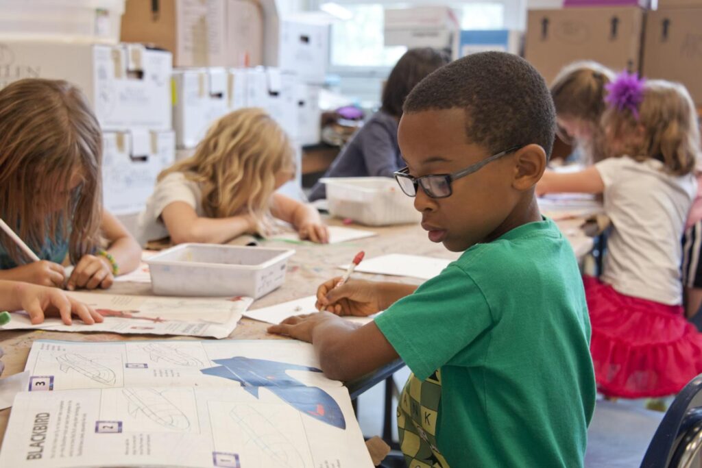 boy in green shirt writing in class