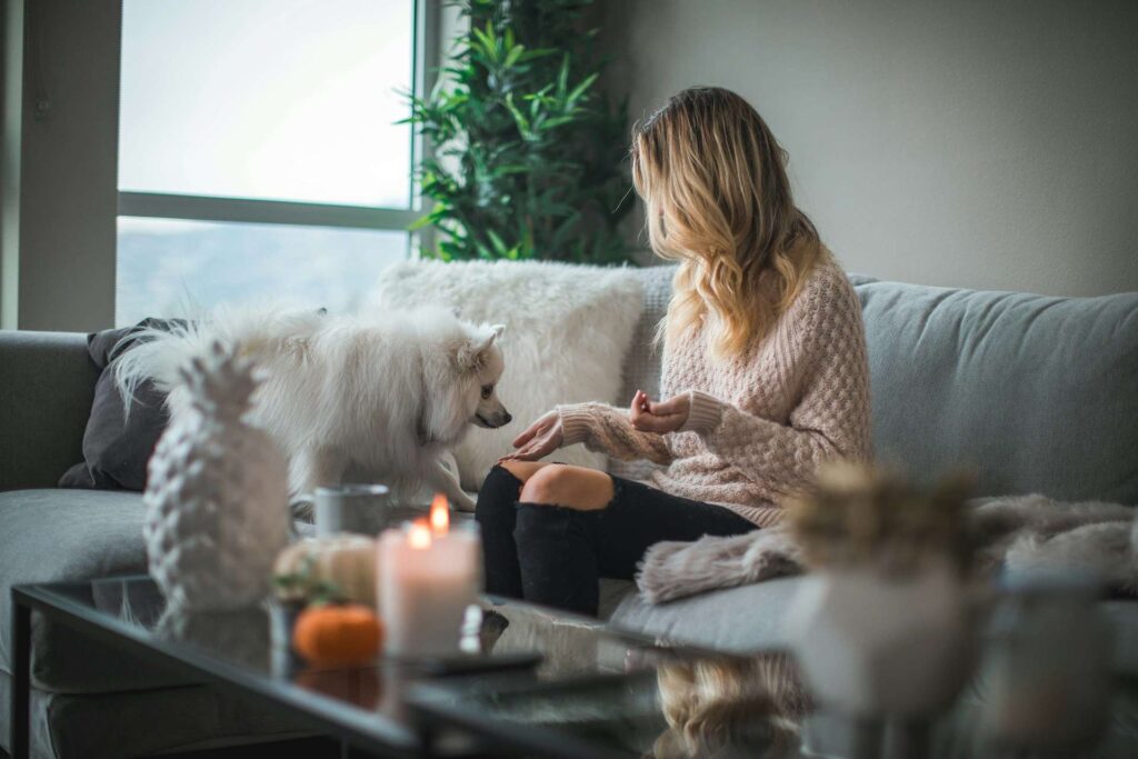 woman in her new living room with a small white dog thanks to first-time homebuyer programs