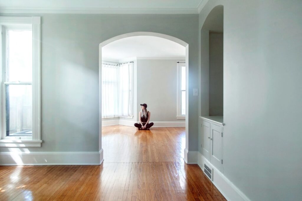 A woman sitting on a floor of an empty apartment.