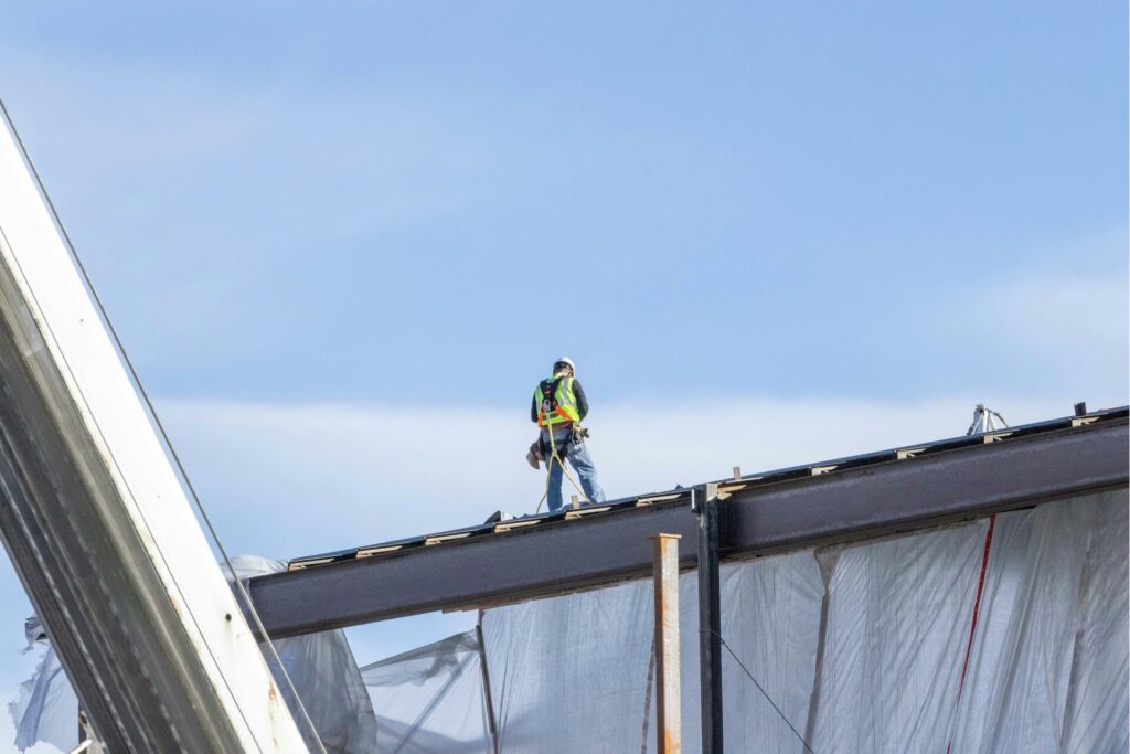 A roofer standing on a roof under construction.