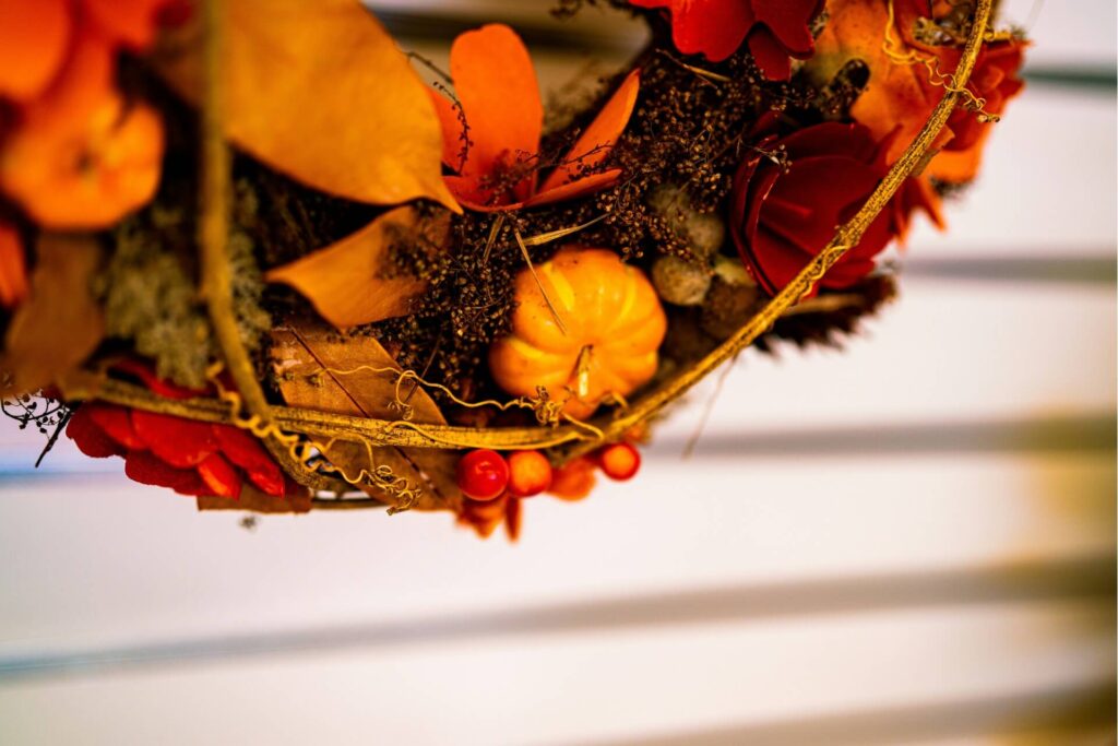 A close-up of a Thanksgiving wreath adorned with pumpkins, berries, flowers and vines.