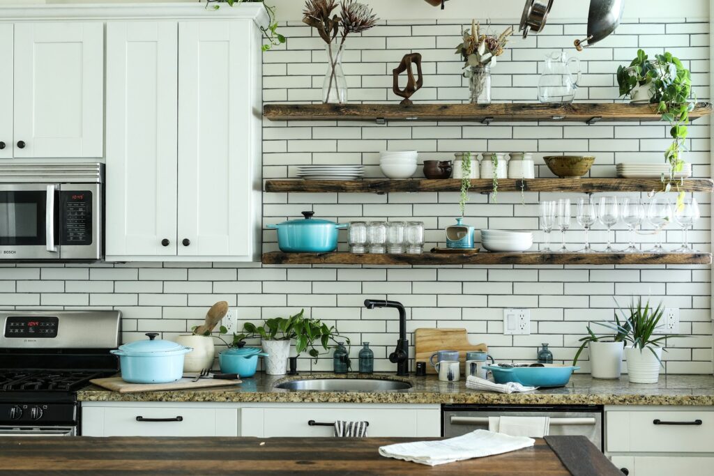 Kitchen counter organization using storage shelves to hold cups and pots.