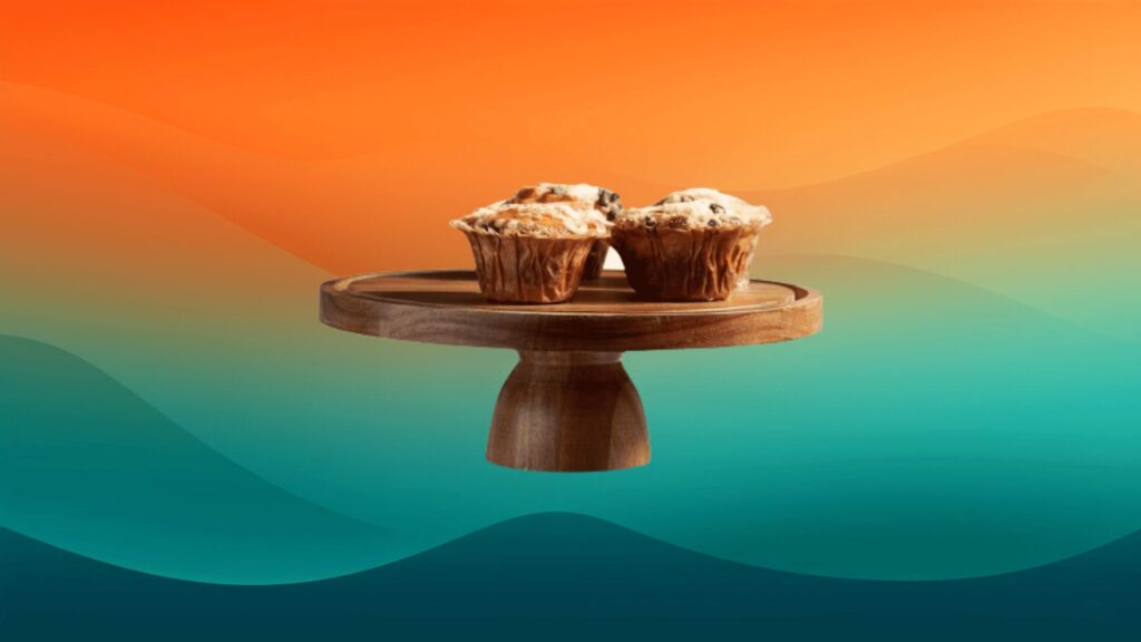 wooden cake stand with muffins on top in front of an orange and teal background