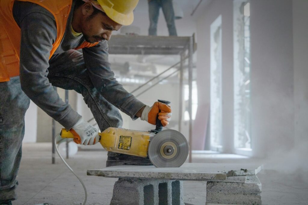 A construction worker operating a handheld concrete saw.