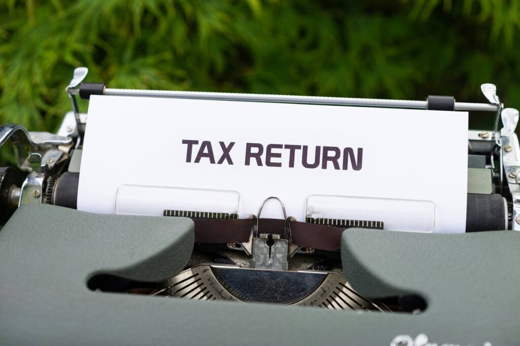 The word tax return printed on a sheet of paper fed into a typewriter.