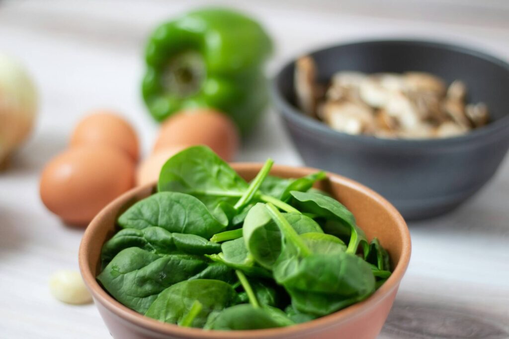 A close-up for spinach leaves with other food items in the background.