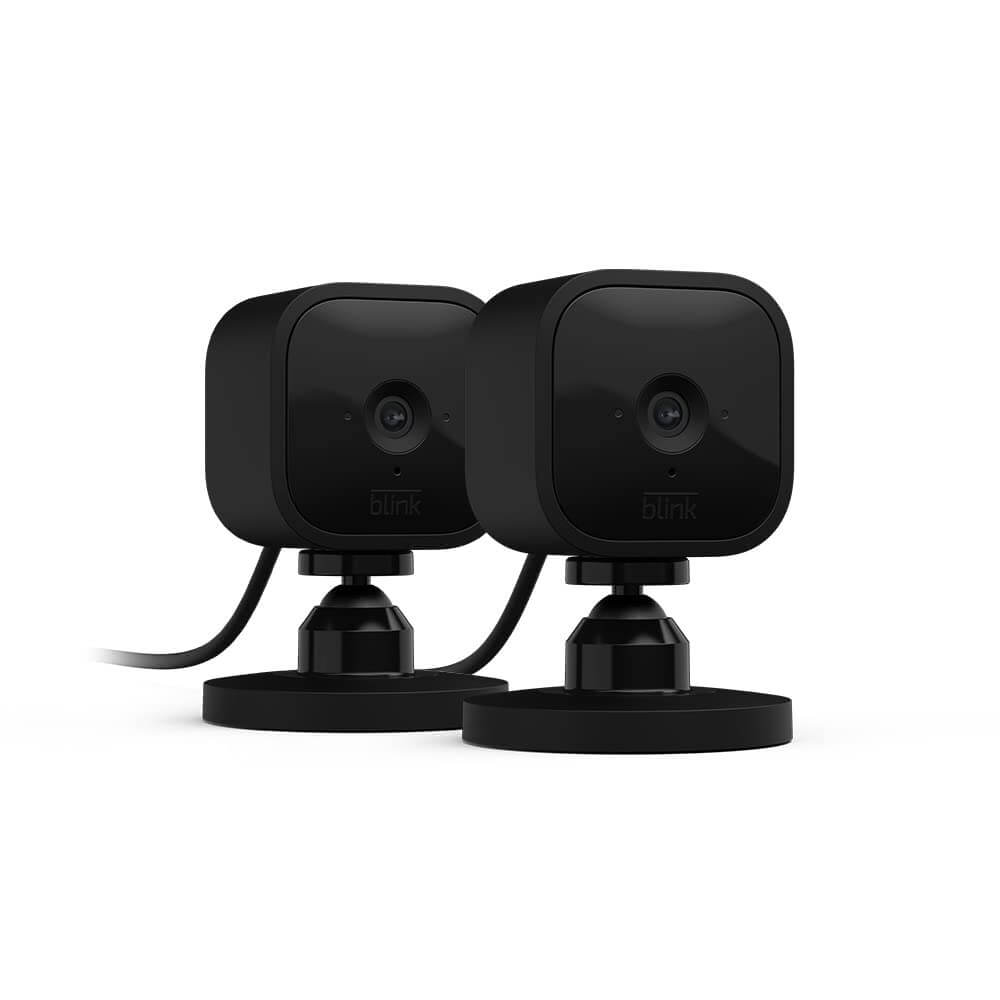 Two mini black Blink indoor cameras with wires trailing off the left side of the image sit against a white background.