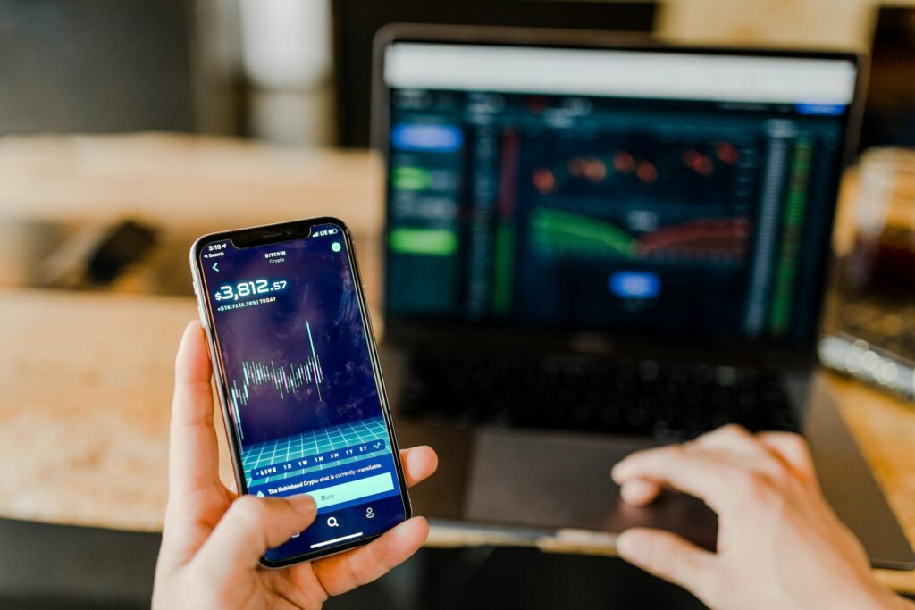 Person checking their investments on the phone and laptop.