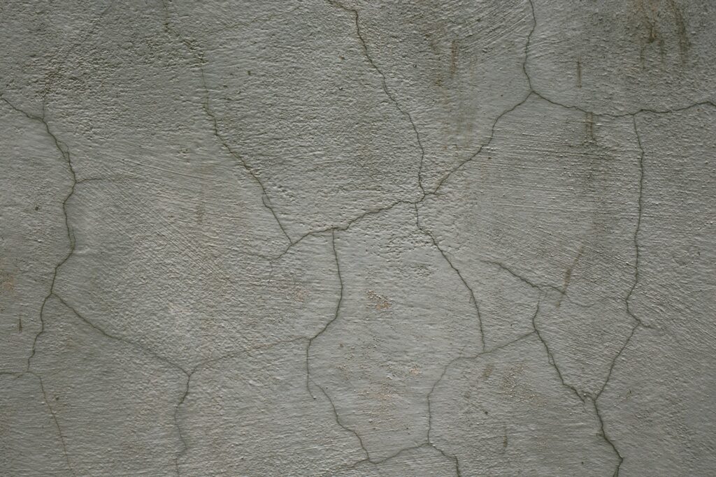 An aged, beige wall has multiple cracks running through it. The cracks could be a sign that there's an issue with the foundation, which is something homeowners wondering how much foundation repairs are should know.