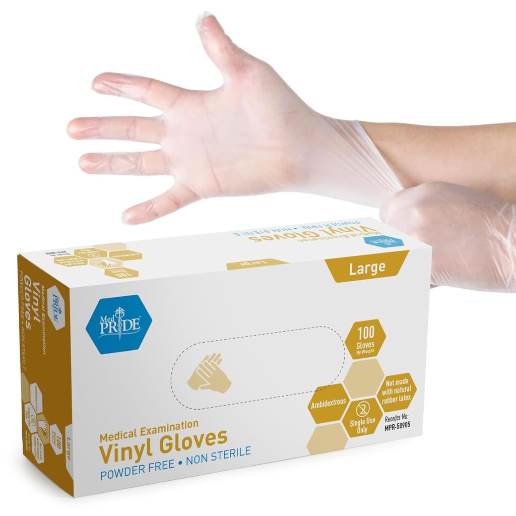 A white and yellow box of vinyl gloves sits against a white background. A person pulls one of the gloves over their open hand above the box.
