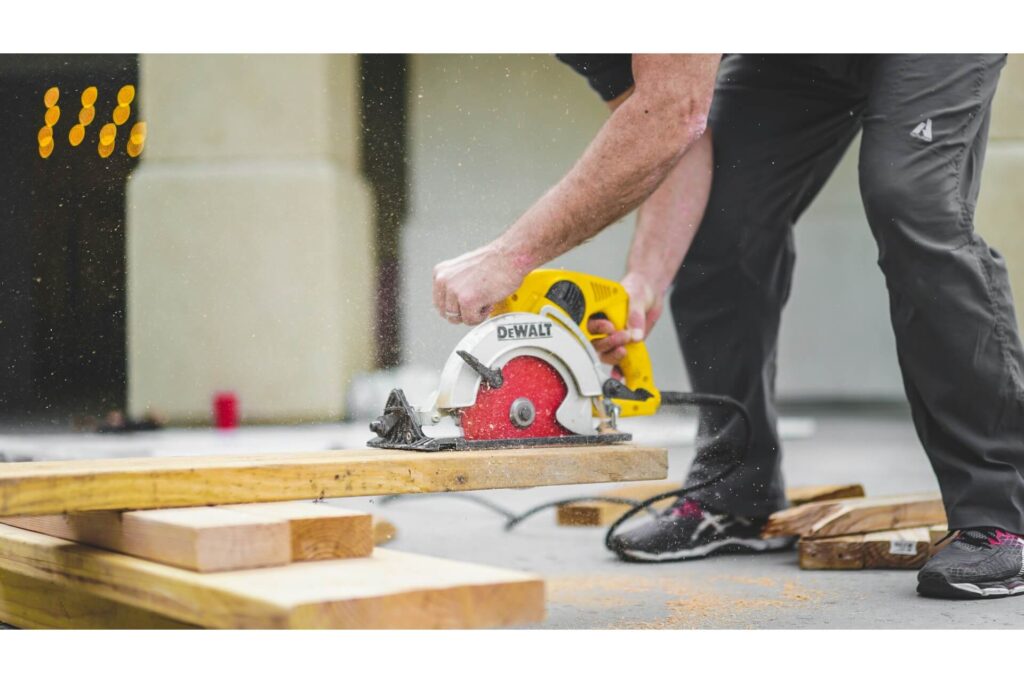 A construction worker using an electric saw to cut a wooden plank