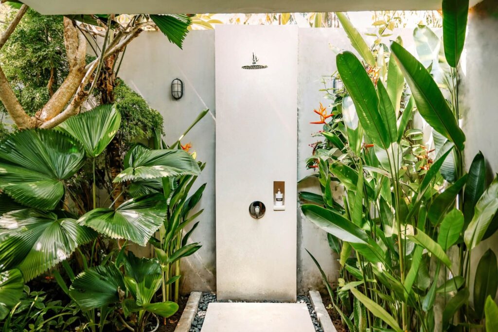 A private outdoor shower flanked by tall plants