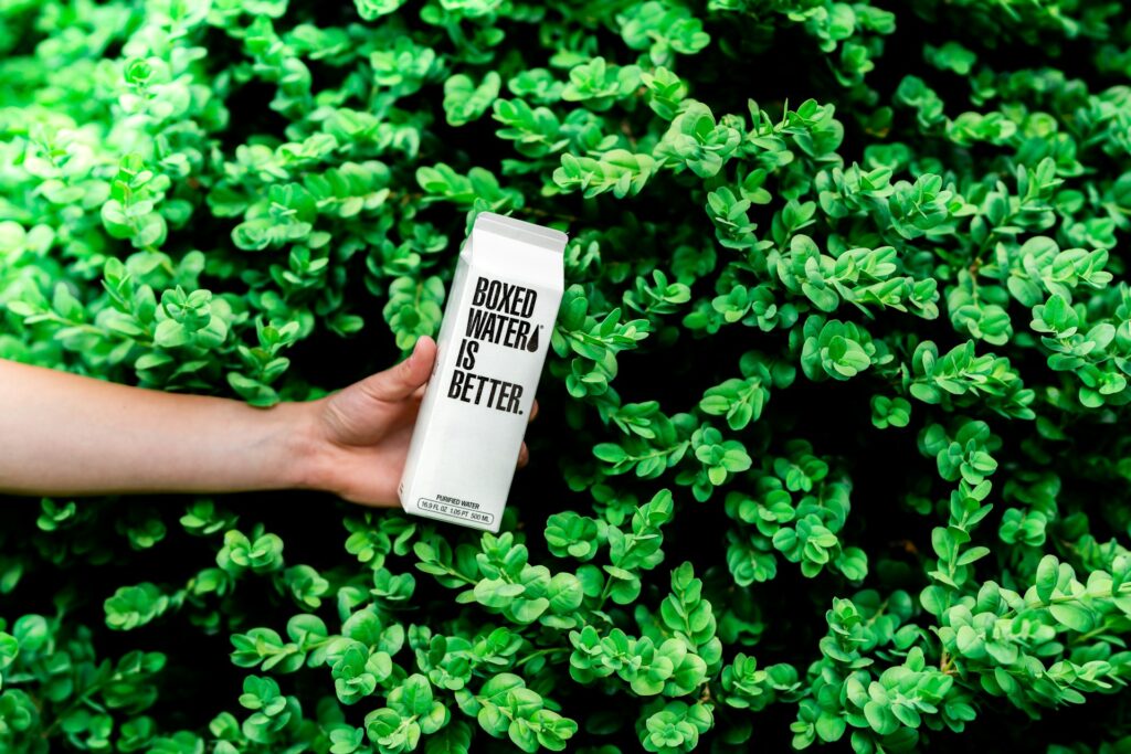 Boxed water in front of bushes.