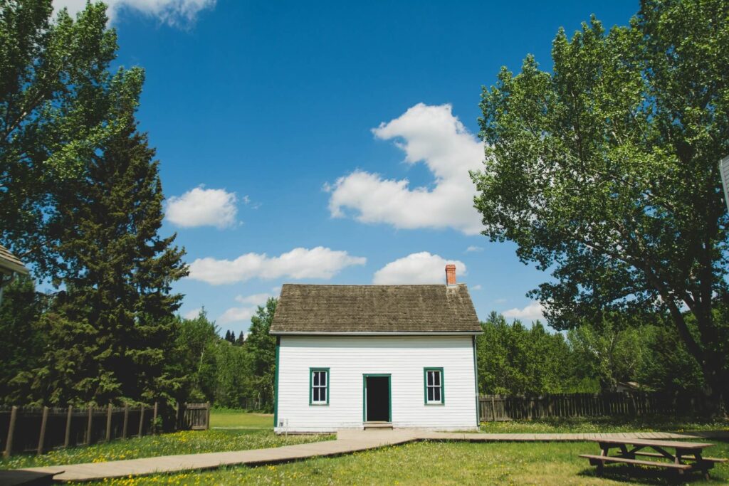 A lone small white house surroundeded by trees