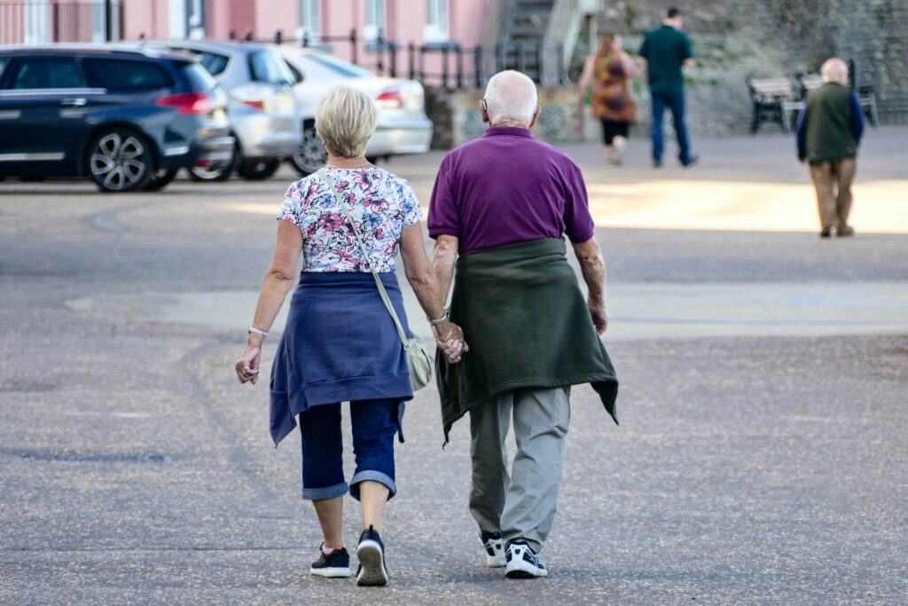 A senior couple walking outside while holding hands