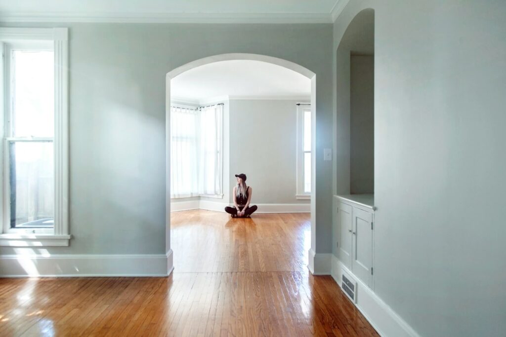 A woman sitting on the floor of an empty apartment