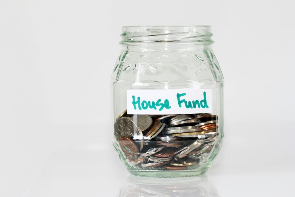 An open jar labeled House Fund filled with coins