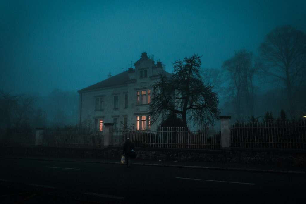 A person walking toward a home against a misty backdrop