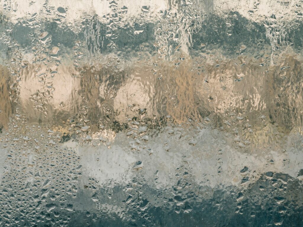 Humidity is collecting on a window. There's too much water on the glass to see through it.