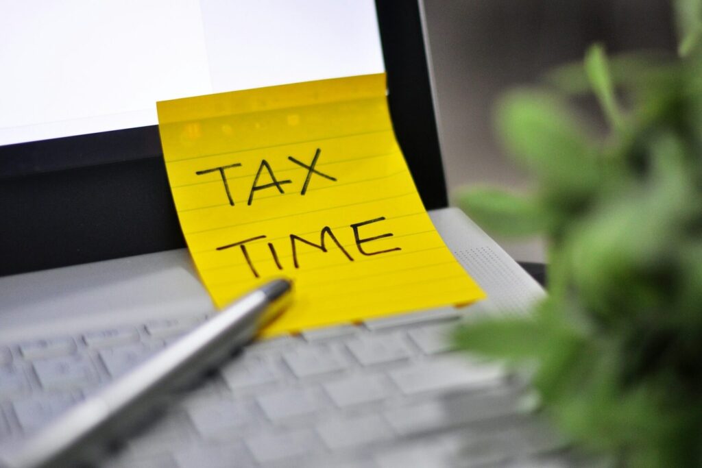 A paper note that says tax time on a laptop