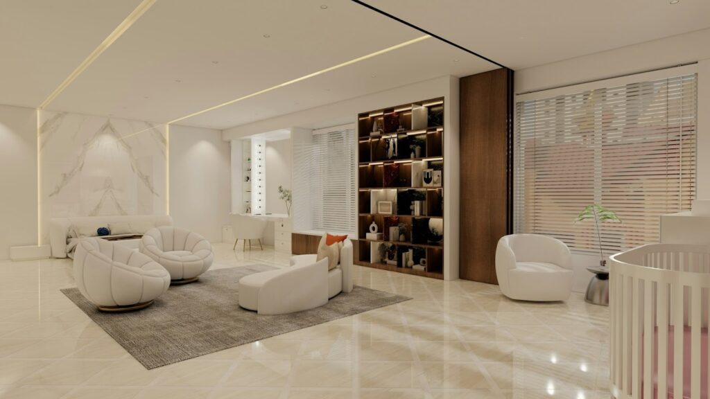 A modern, elegant living room with cream tones. It features plush white chairs, a soft rug, bookshelves, and soft lighting, creating a calm, inviting ambience