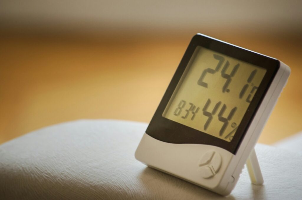A white and black hygrometer sits on an indoor surface so someone can understand the best humidity level for their home.