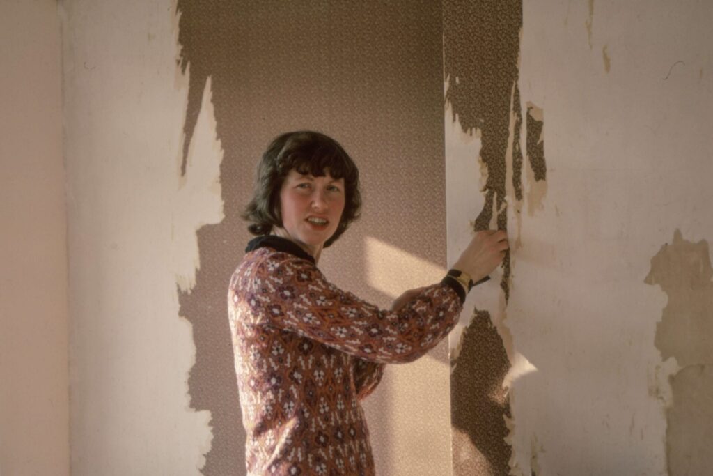 A woman removing wallpaper