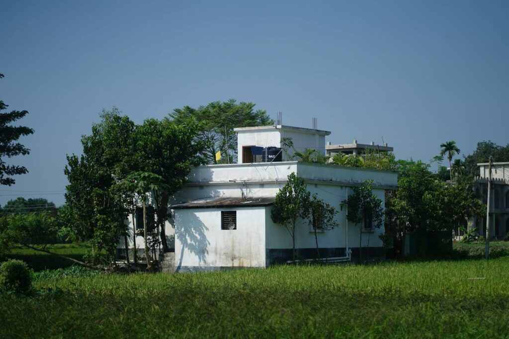 White home surrounded by lush green trees and grass